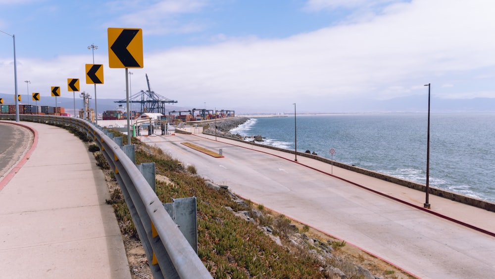 a road with a body of water and a bridge in the background