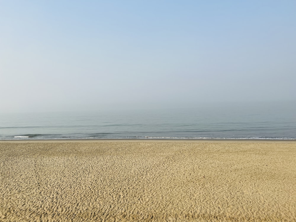 a sandy beach with water in the background