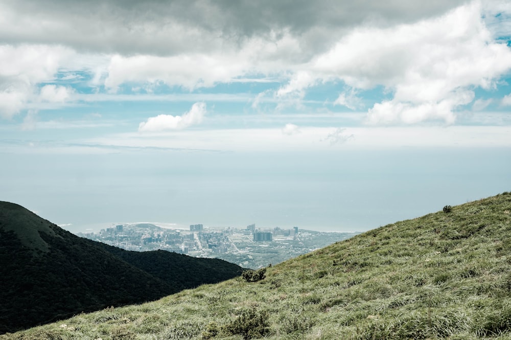 a grassy hill with a city in the distance