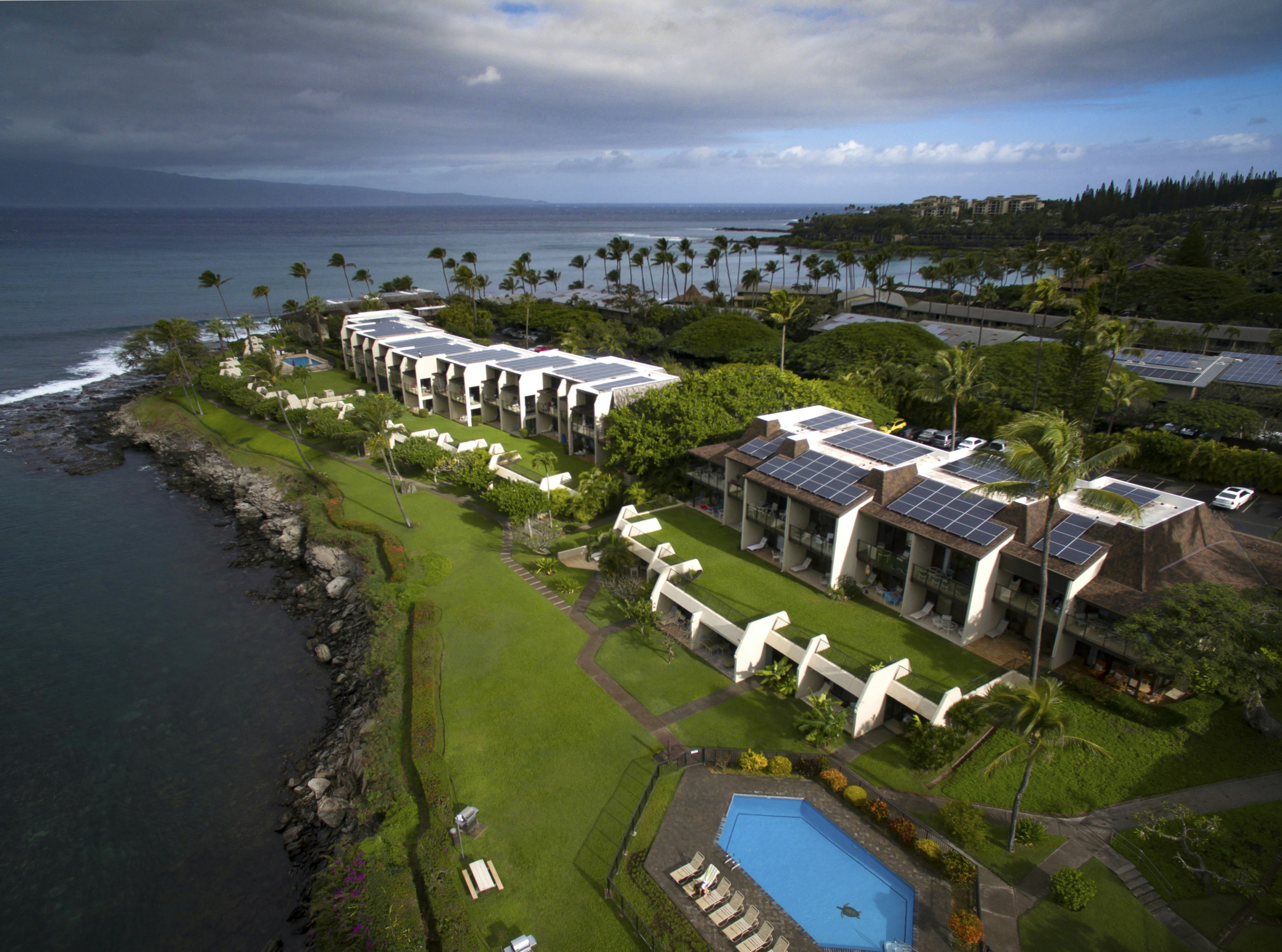 a building with a pool and trees by the water, 