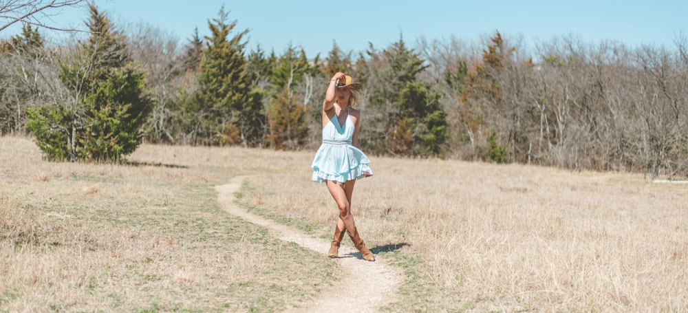 a person in a dress walking on a dirt path in a field