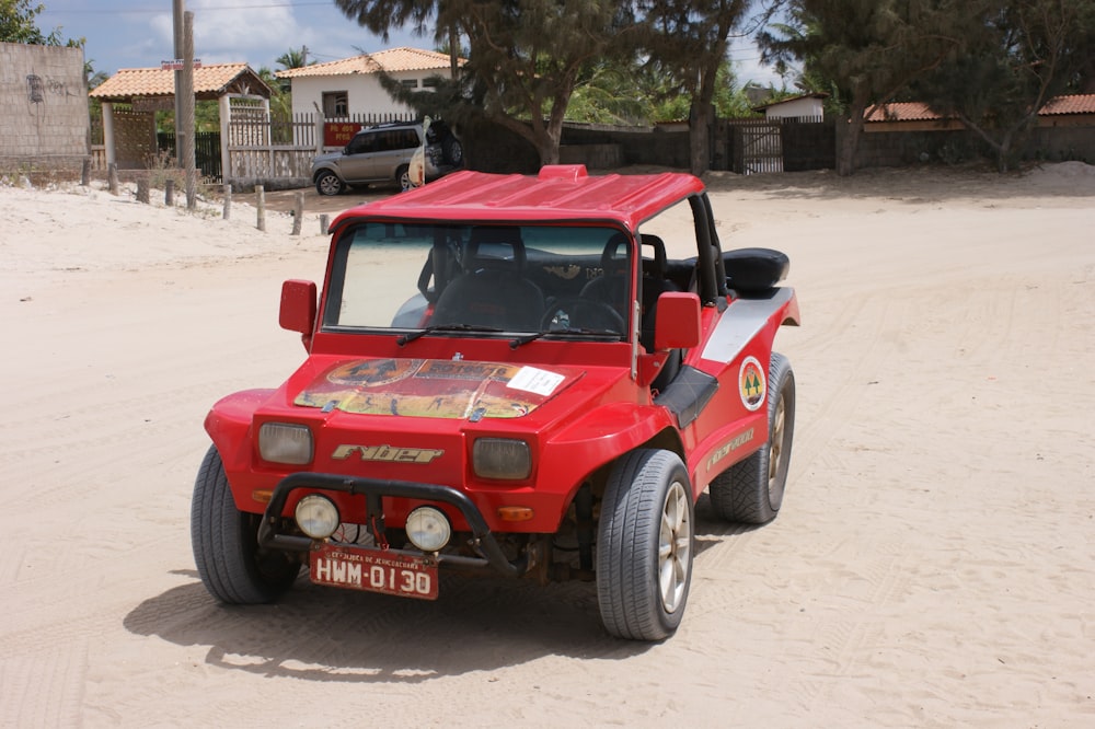 a red car parked on a sandy road