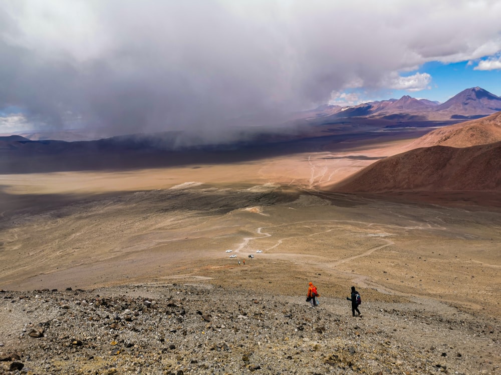 two people walking on a rocky terrain