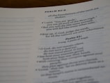 Close-up view of a page from the Bible, focusing on Psalm 82:6-8. The text discusses themes of divinity and mortality. The page is slightly curled, and the paper appears off-white with printed text in a dark font.