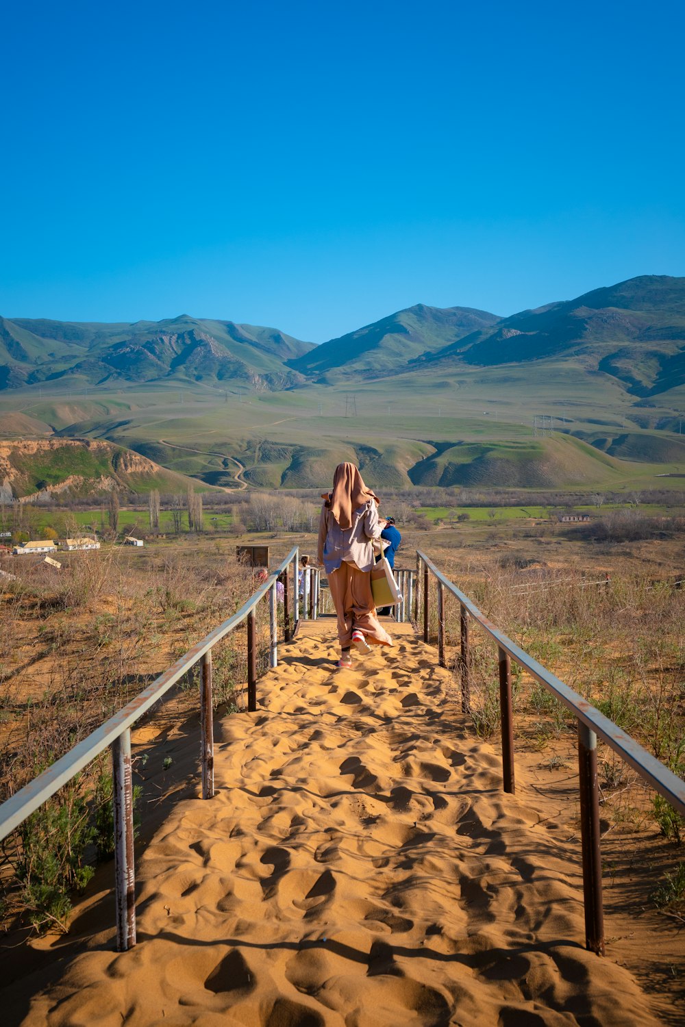 a person and a child walking on a bridge over a valley