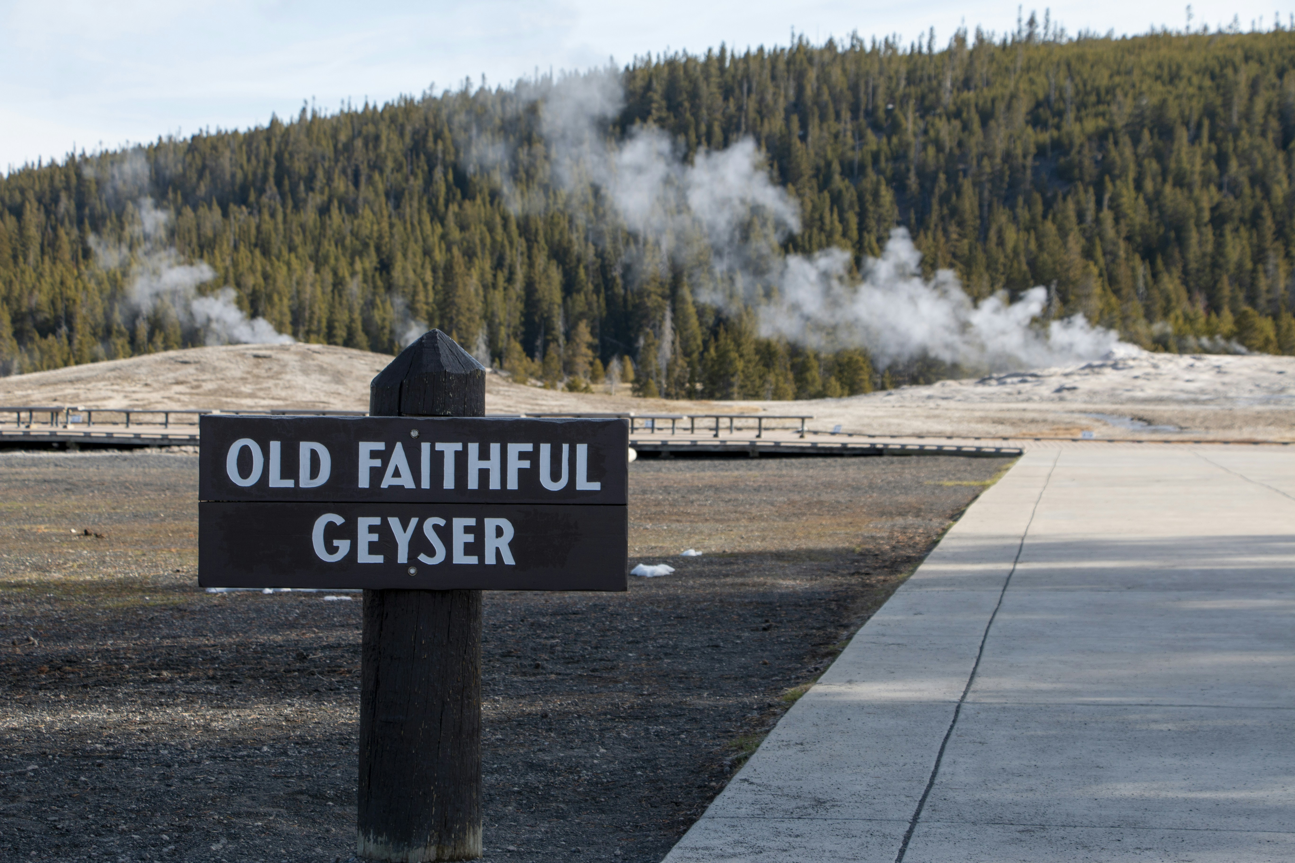 a sign on the side of a road with a large waterfall in the background