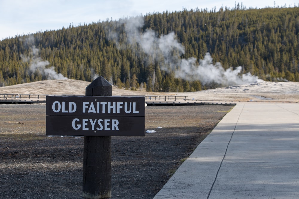 a sign on the side of a road with a large waterfall in the background