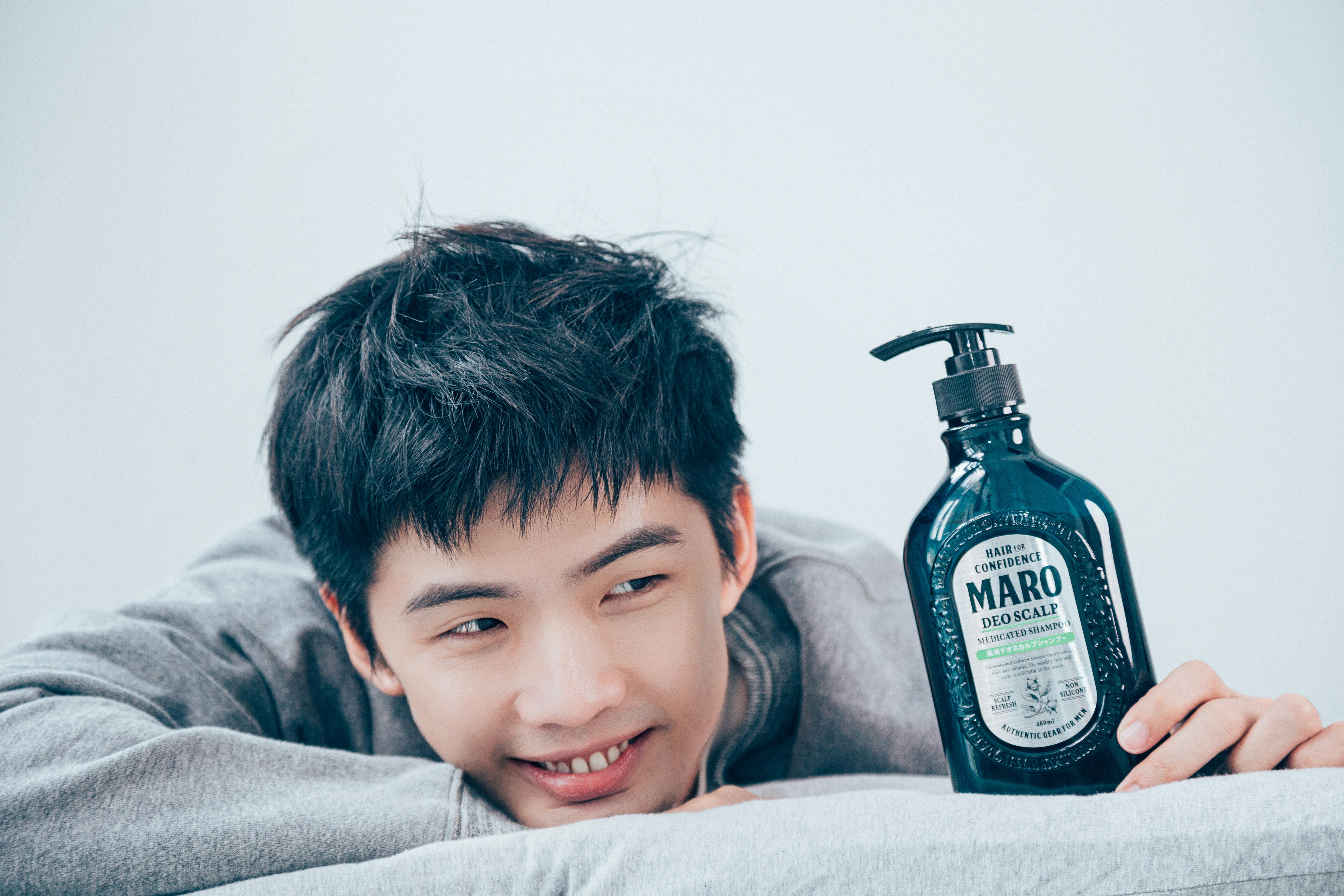 a boy lying on a bed with a bottle of alcohol on his head