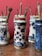 Several ornate ceramic jars, each decorated with intricate blue patterns on a white background, hold collections of paintbrushes. The jars are arranged on a wooden surface against a red wall.
