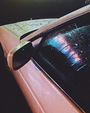 Close-up of a microfiber car wash glove absorbing water on a shiny car surface.