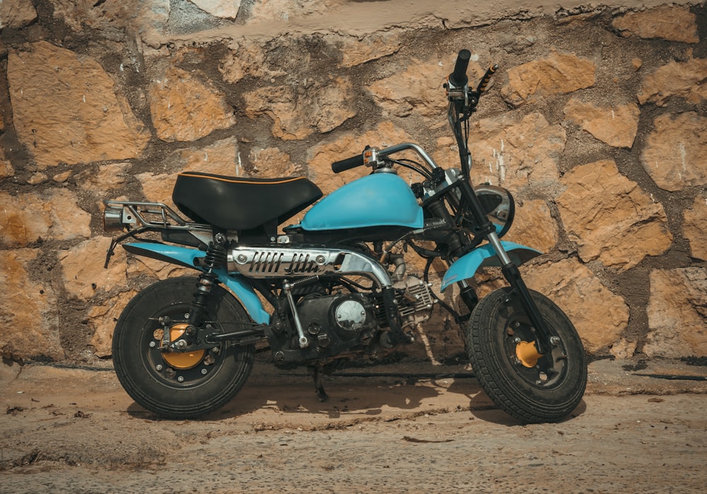 a blue motorcycle parked in front of a rock wall