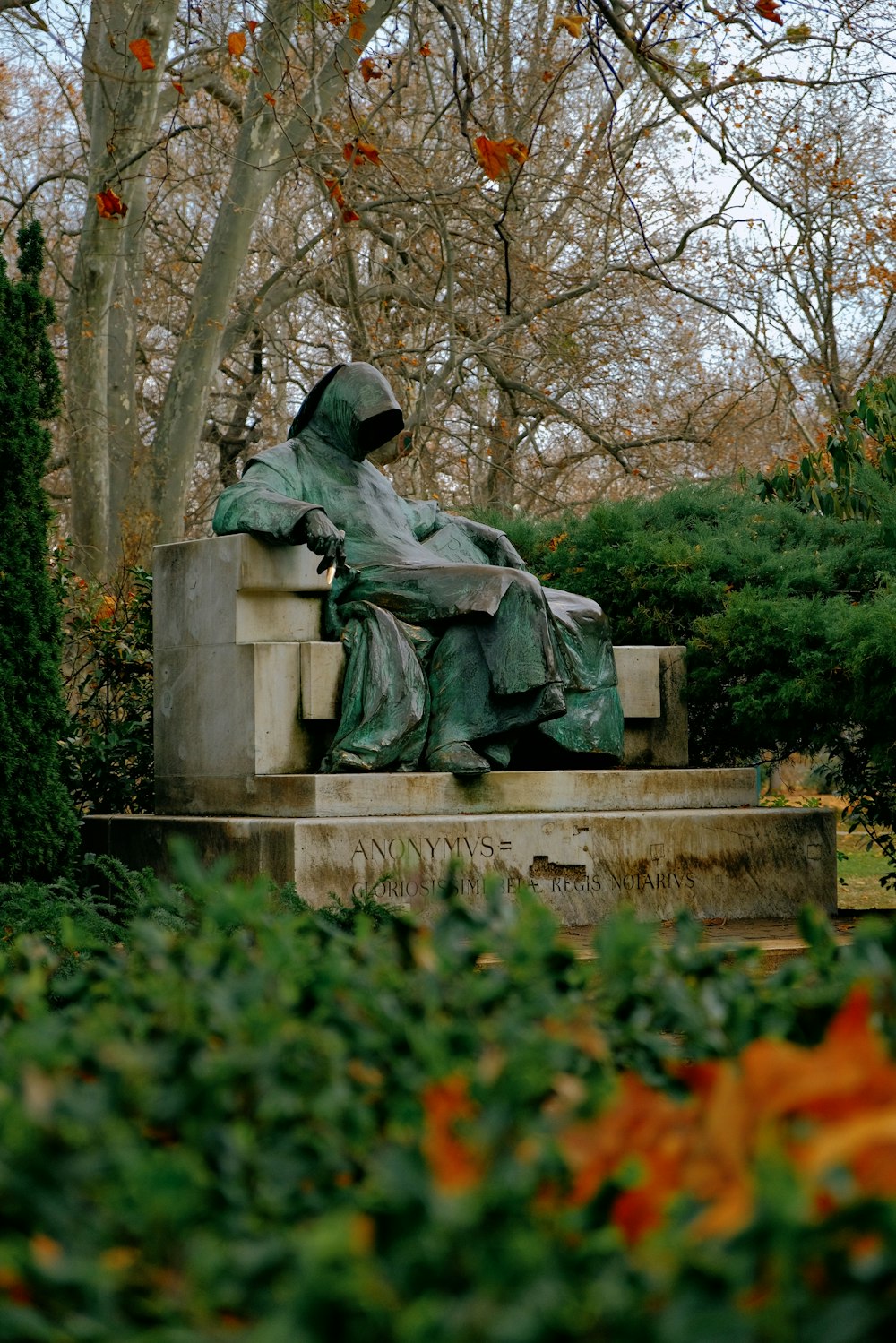 Una statua di una persona seduta su una panchina in un parco