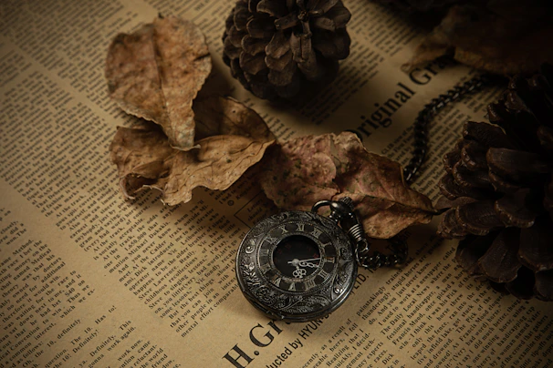A tiny pocket watch pin resting on an open vintage book page with warm lighting