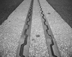 Metal tracks embedded in a concrete surface, featuring a zigzag pattern running parallel to one another.