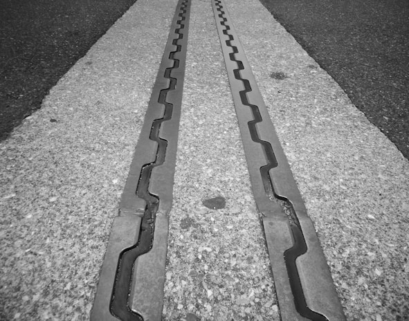 Metal tracks embedded in a concrete surface, featuring a zigzag pattern running parallel to one another.