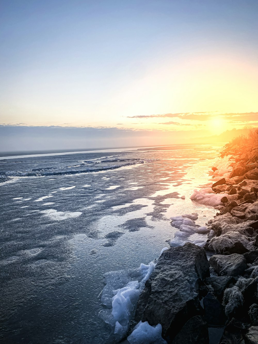 uma praia rochosa com um pôr do sol