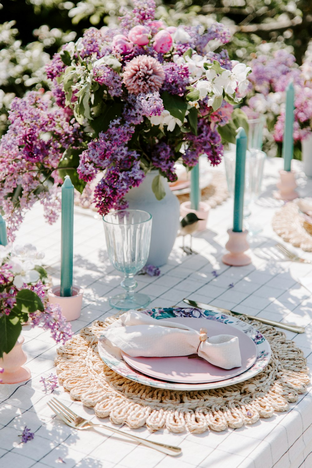 a table with plates and glasses with flowers in the background