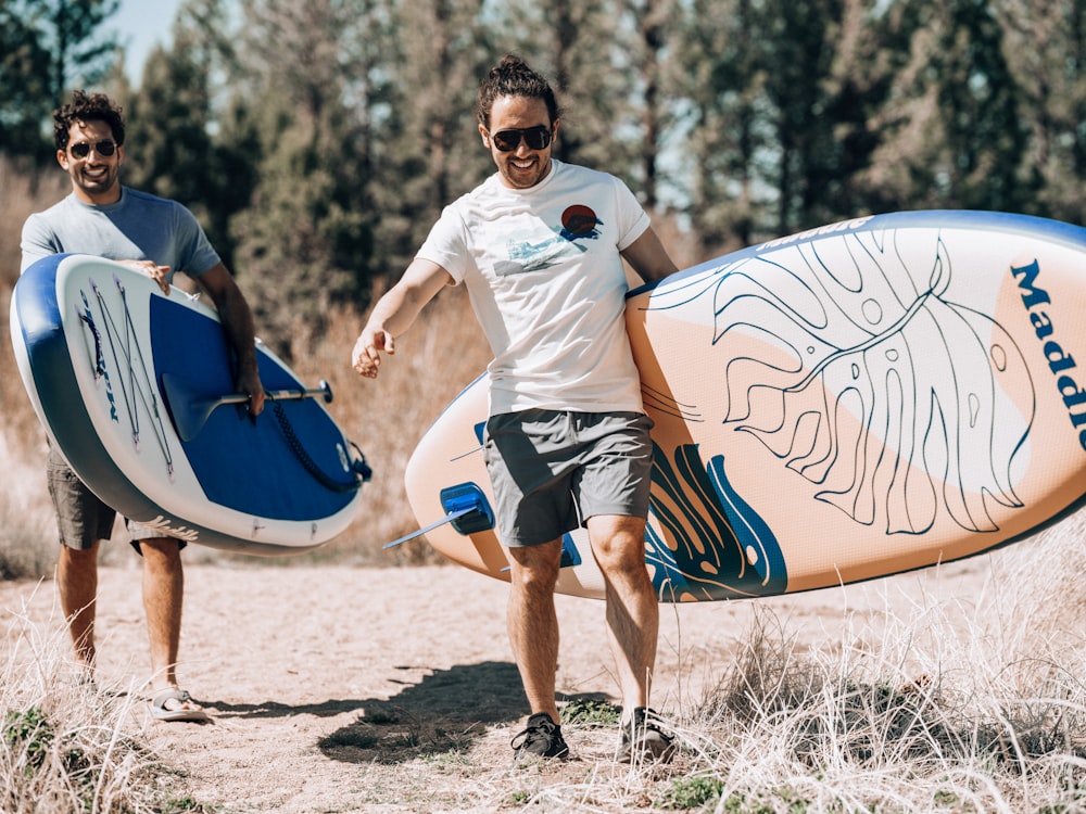 a couple of men carrying surfboards