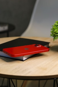 A telephone resting beside a small plant on a wooden table.