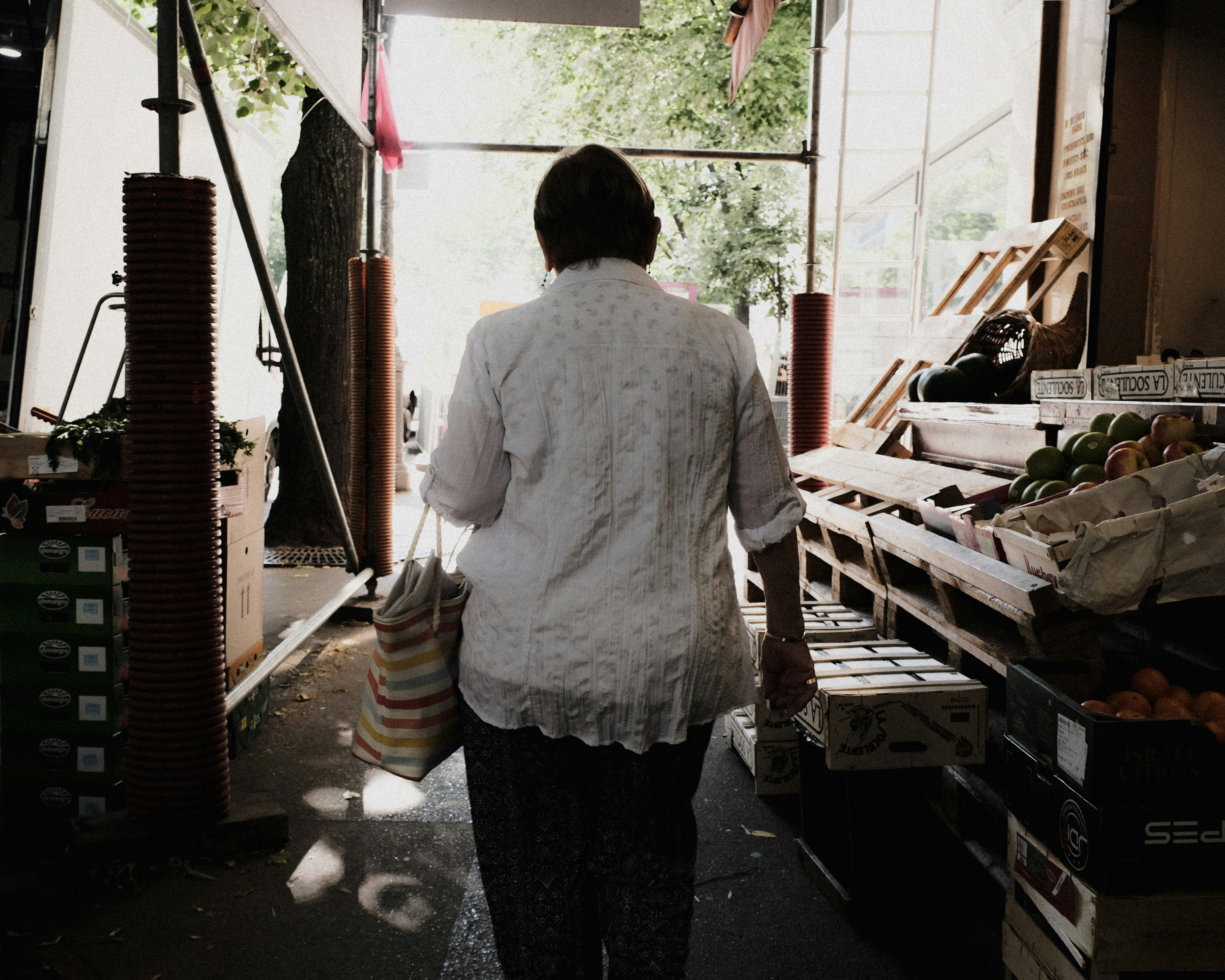 Shopper walking past produce stalls at a market