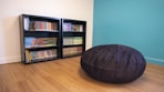 a black bean bag on a wood floor in front of a bookcase