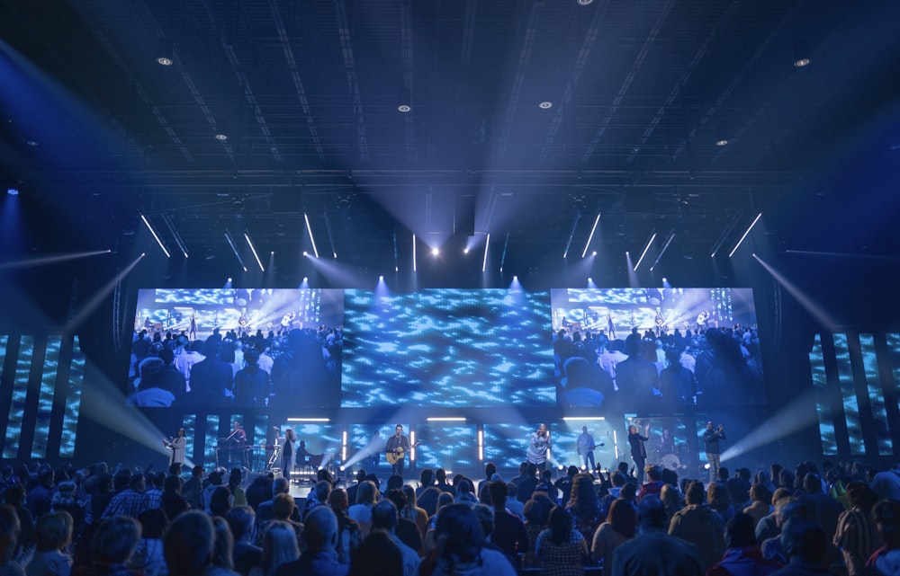 a group of people on a stage with lights and a crowd watching