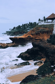 a rocky beach with a building on the shore