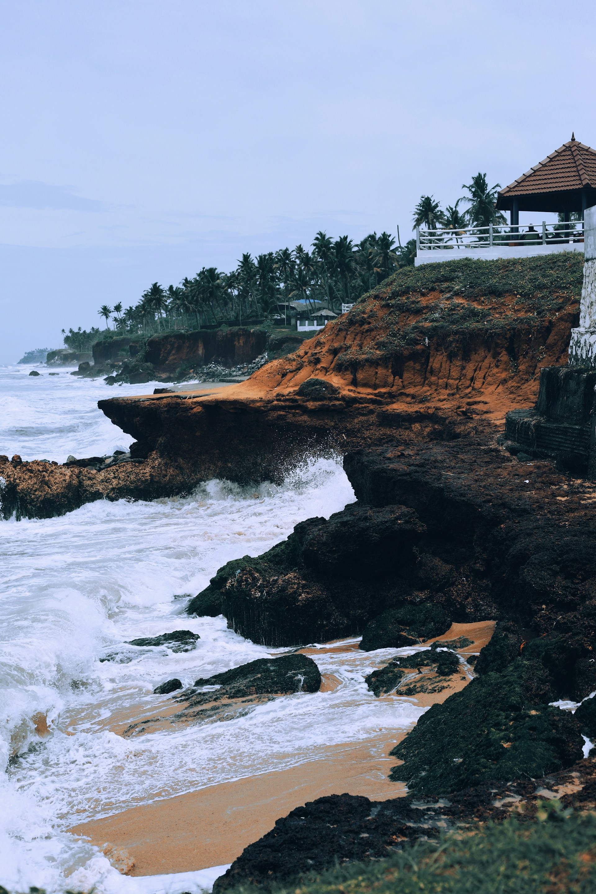 a rocky beach with a building on the shore