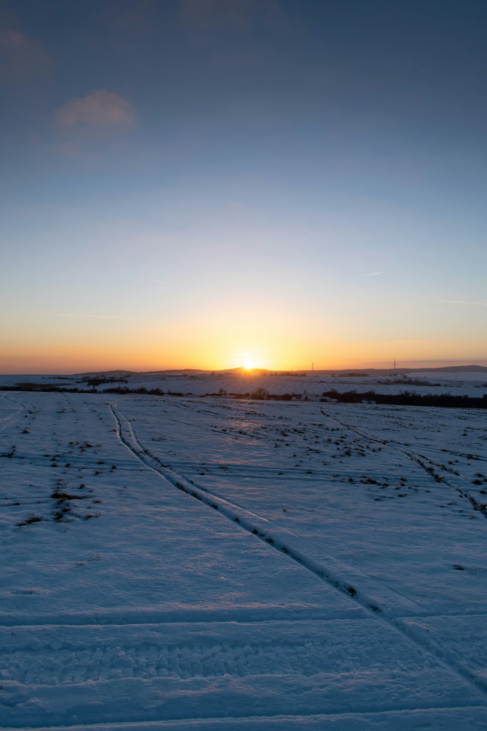 a snowy road with the sun setting