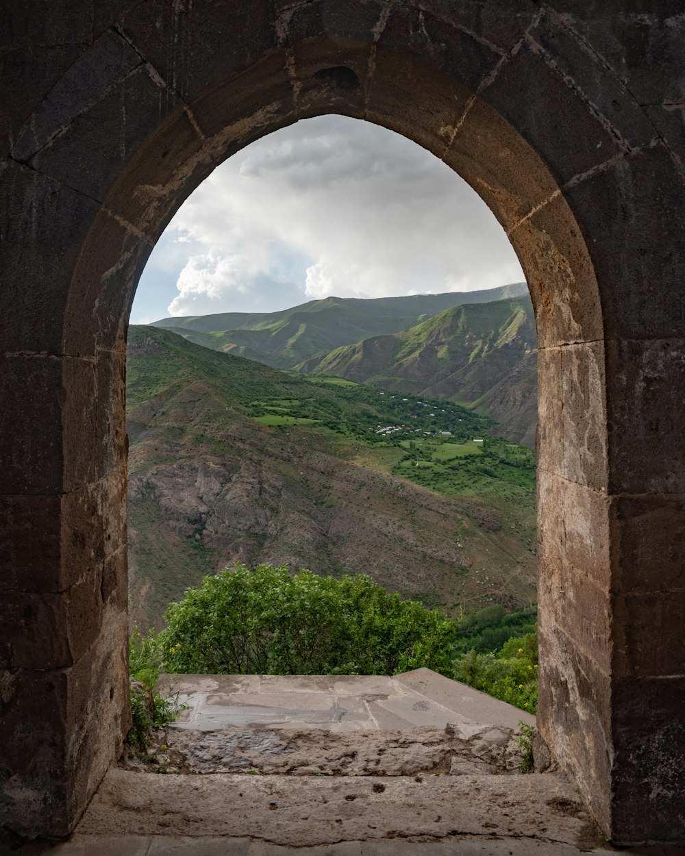 a view of a valley through a stone archway