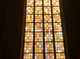Close-up of a handcrafted stained glass panel with warm amber tones glowing in sunlight.