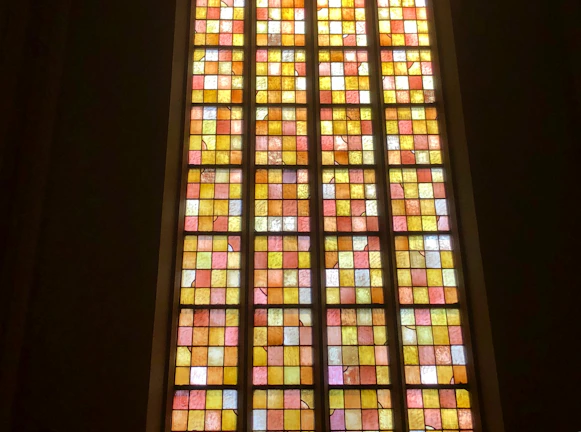 Close-up of a handcrafted stained glass panel with warm amber tones glowing in sunlight.