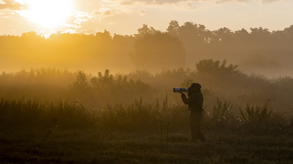 a man holding a camera in a field