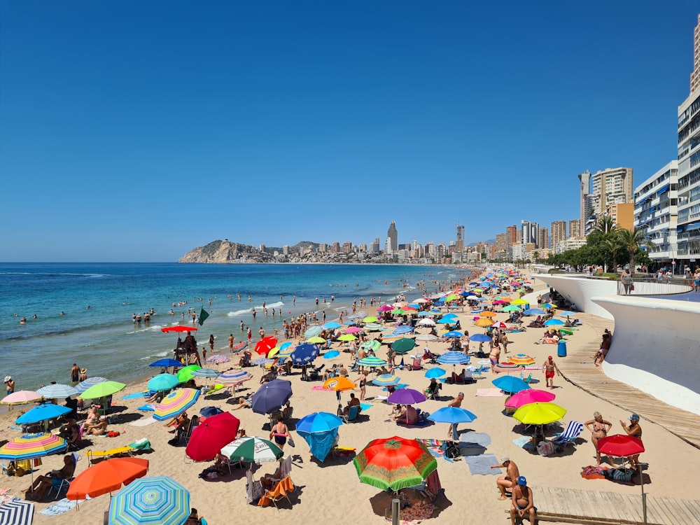 Una playa llena de gente con sombrillas