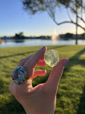 Hand holding a sparkling crystal ring with sunlight highlighting its facets