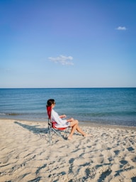 a person sitting on a chair on a beach