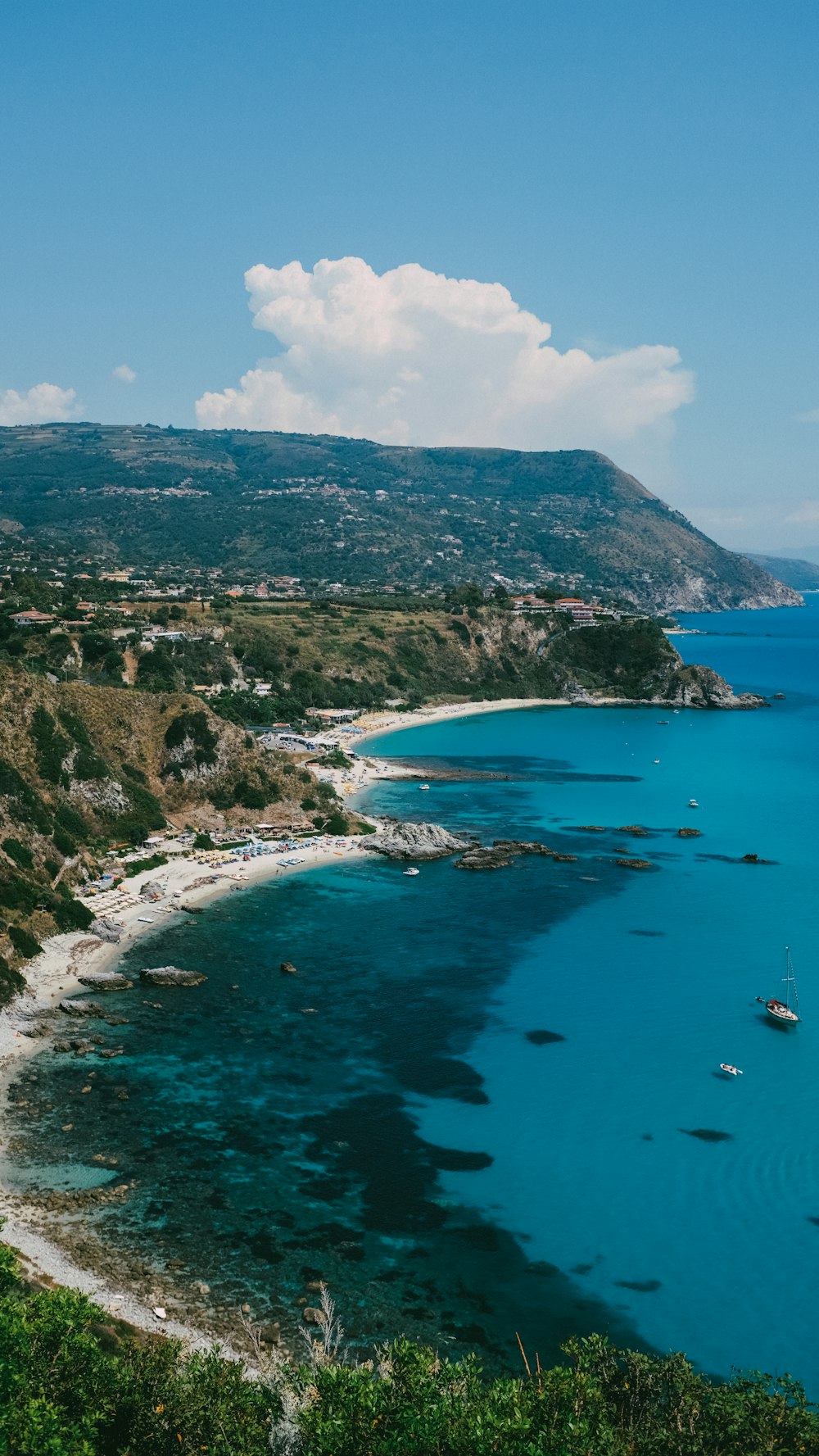 a beach with blue water and a town in the distance