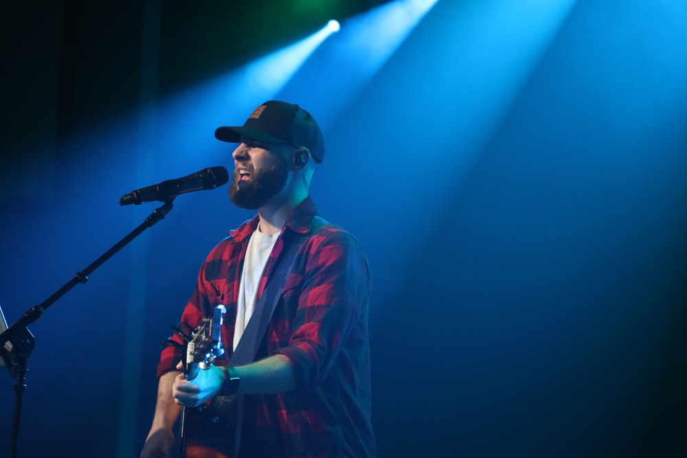 a man with a beard and a hat with a microphone on a stage