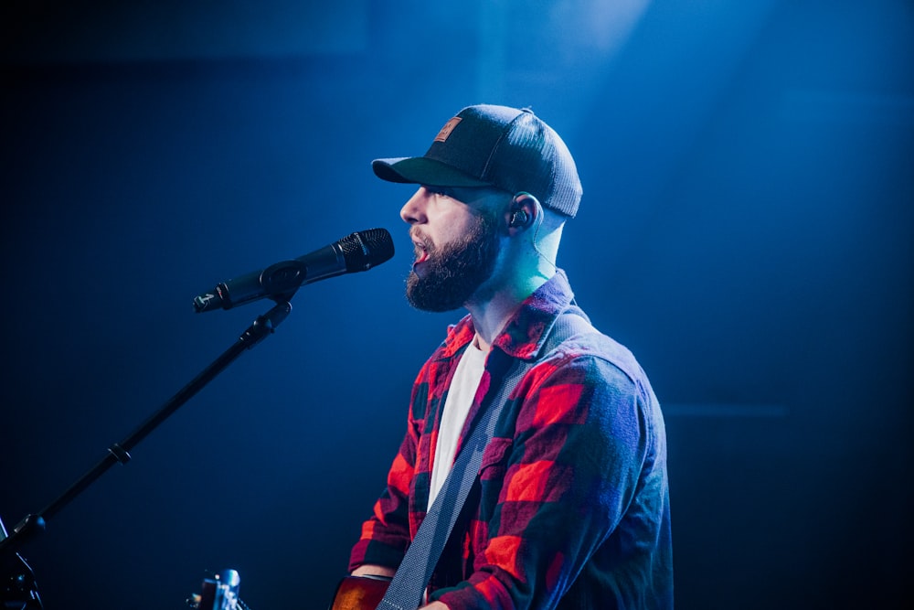 a man with a beard and a hat singing into a microphone