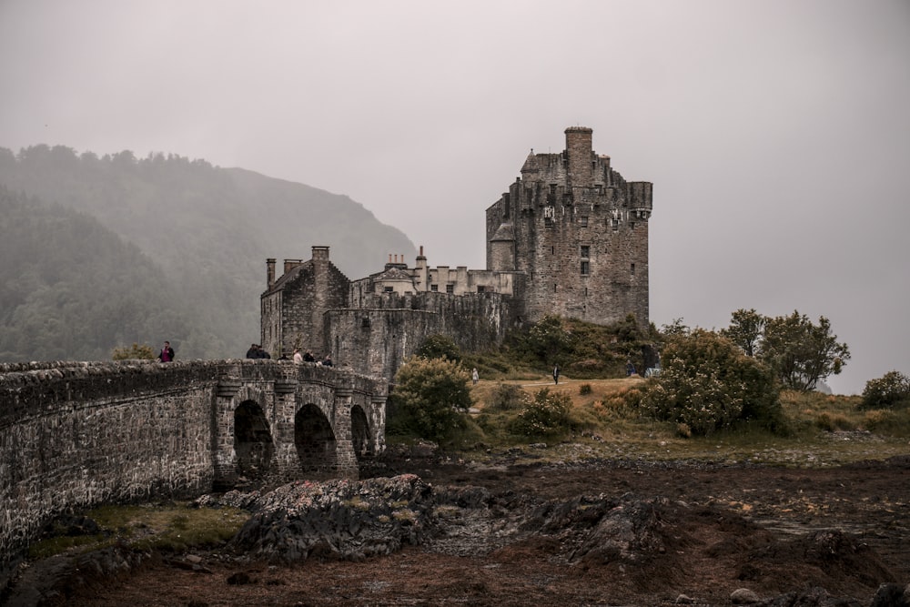 a stone castle on a hill with Eilean Donan in the background