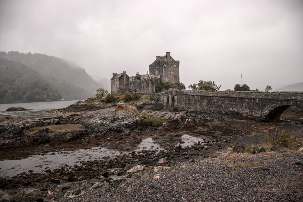 a stone castle on a hill with Eilean Donan in the background