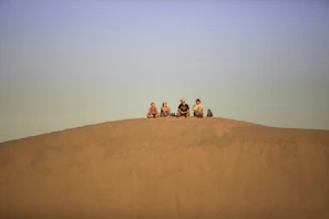 a group of people sitting on a sand dune