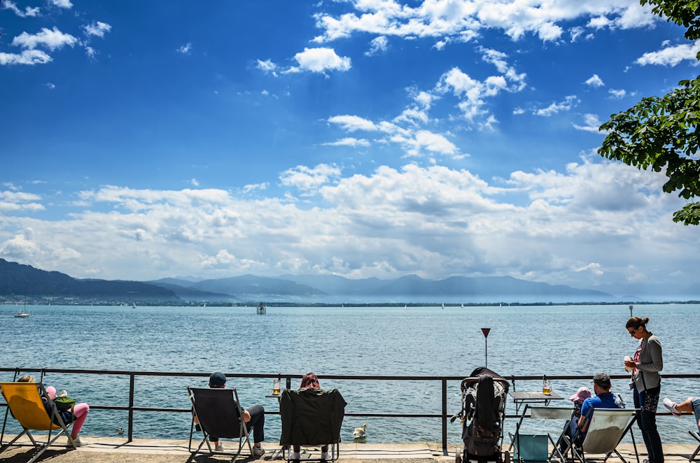 people sitting on a deck overlooking a body of water