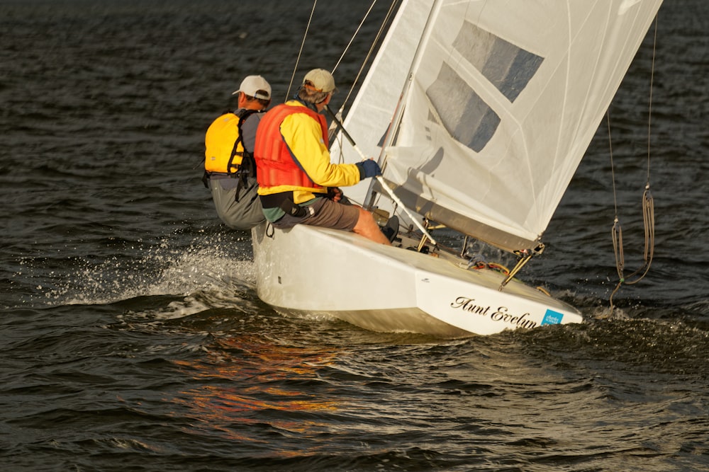 men in orange vests sailing on a sailboat