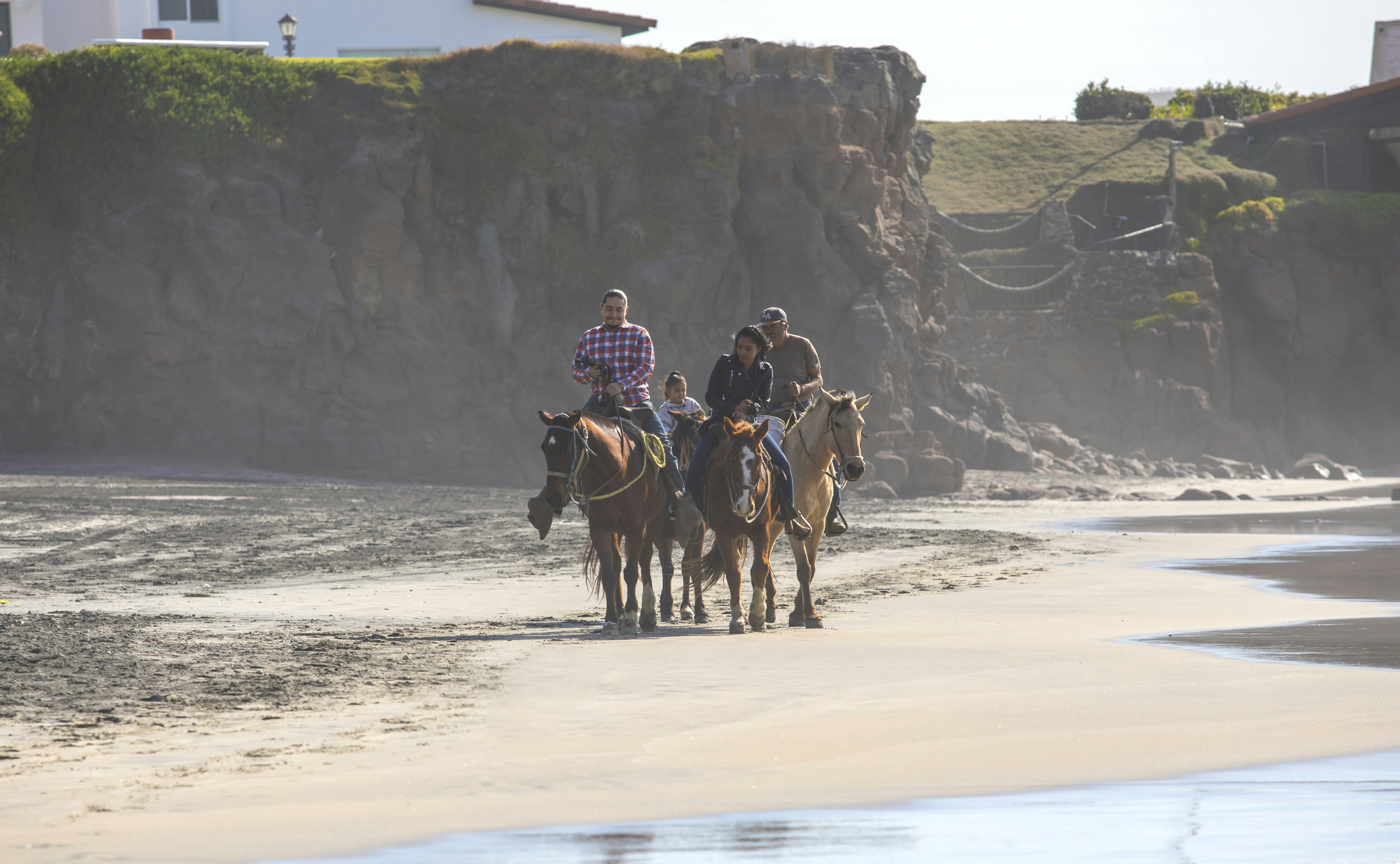 people riding horses on a beach