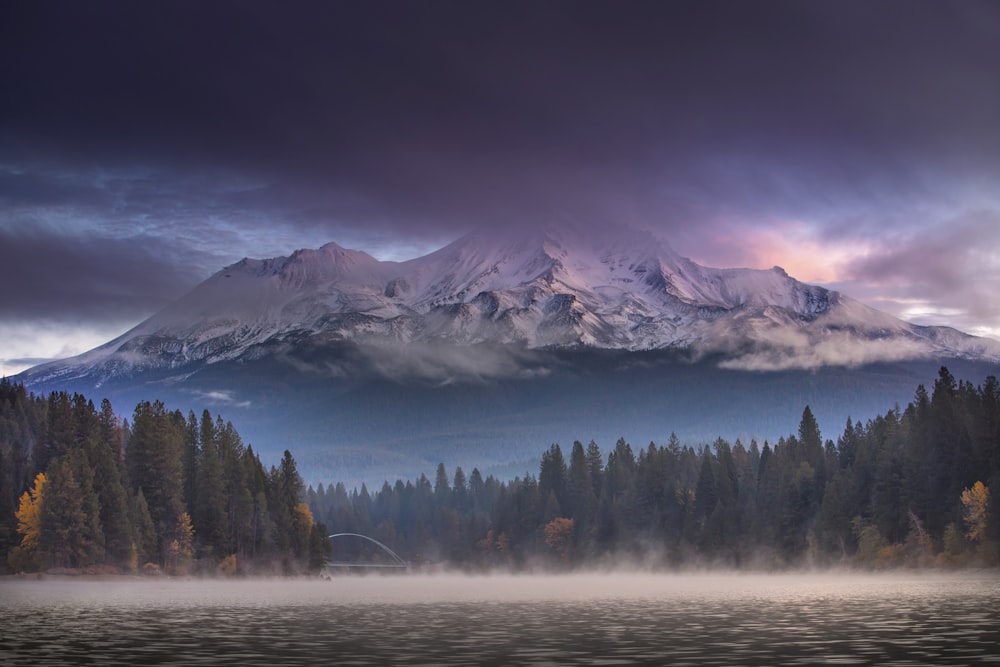 a lake with trees and mountains in the background