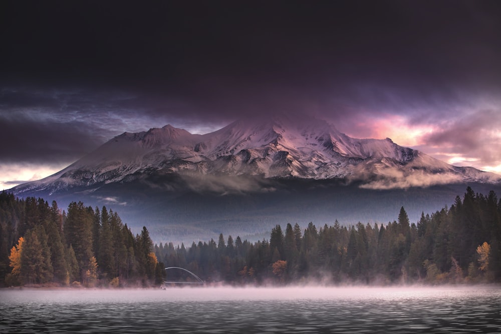 a lake with trees and mountains in the background