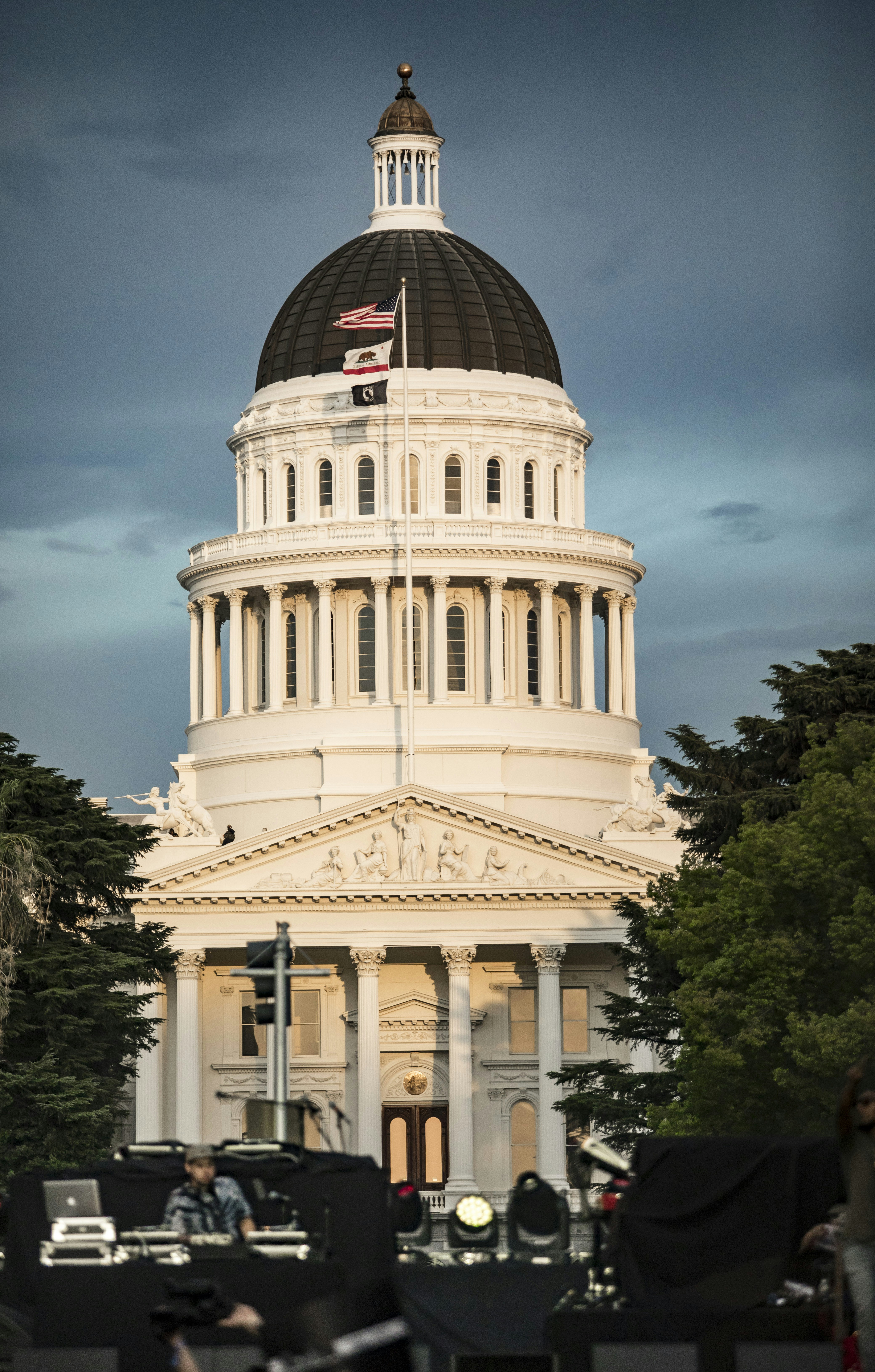 a white building with a dome and a flag on top with California State Capitol in the background