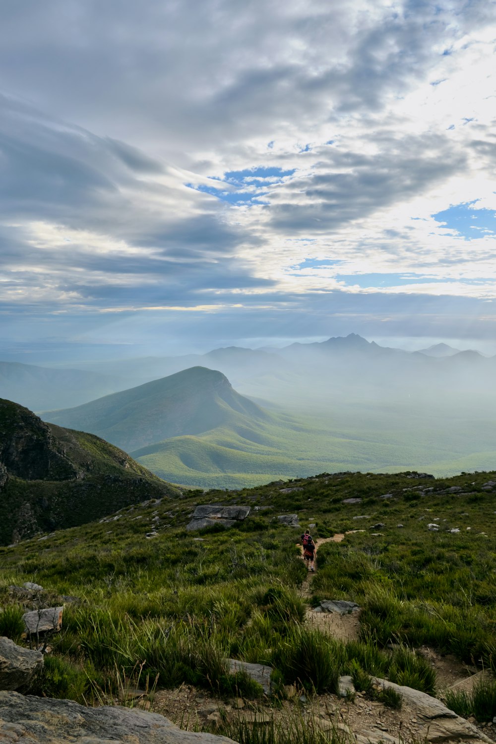 a person walking on a trail in a valley with mountains in the background