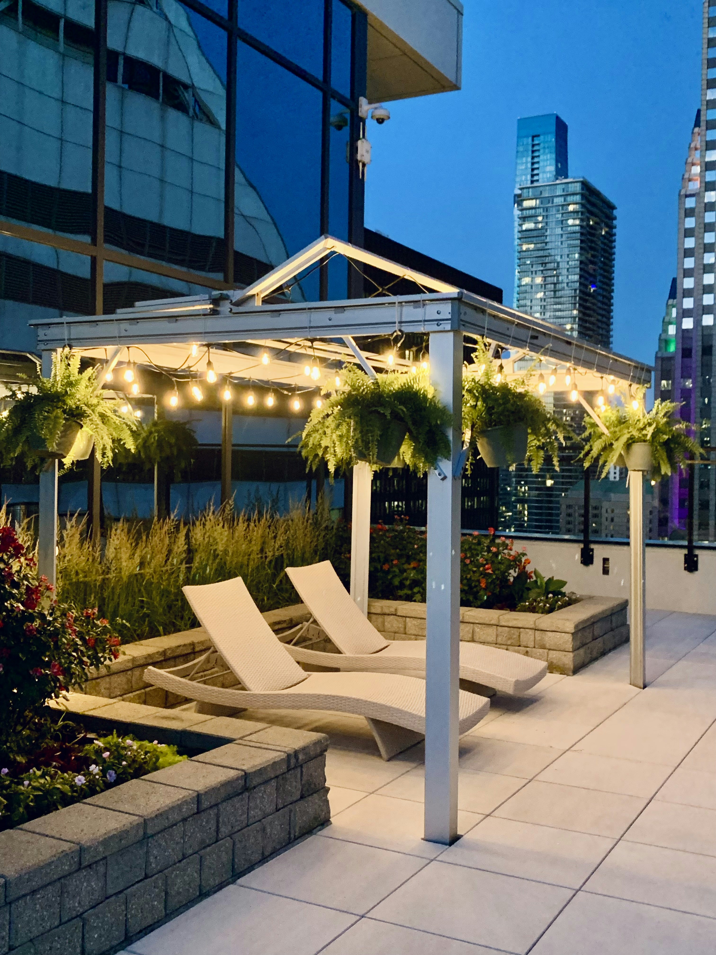 Rooftop corporate event with city skyline backdrop, modern lounge furniture, and ambient string lighting